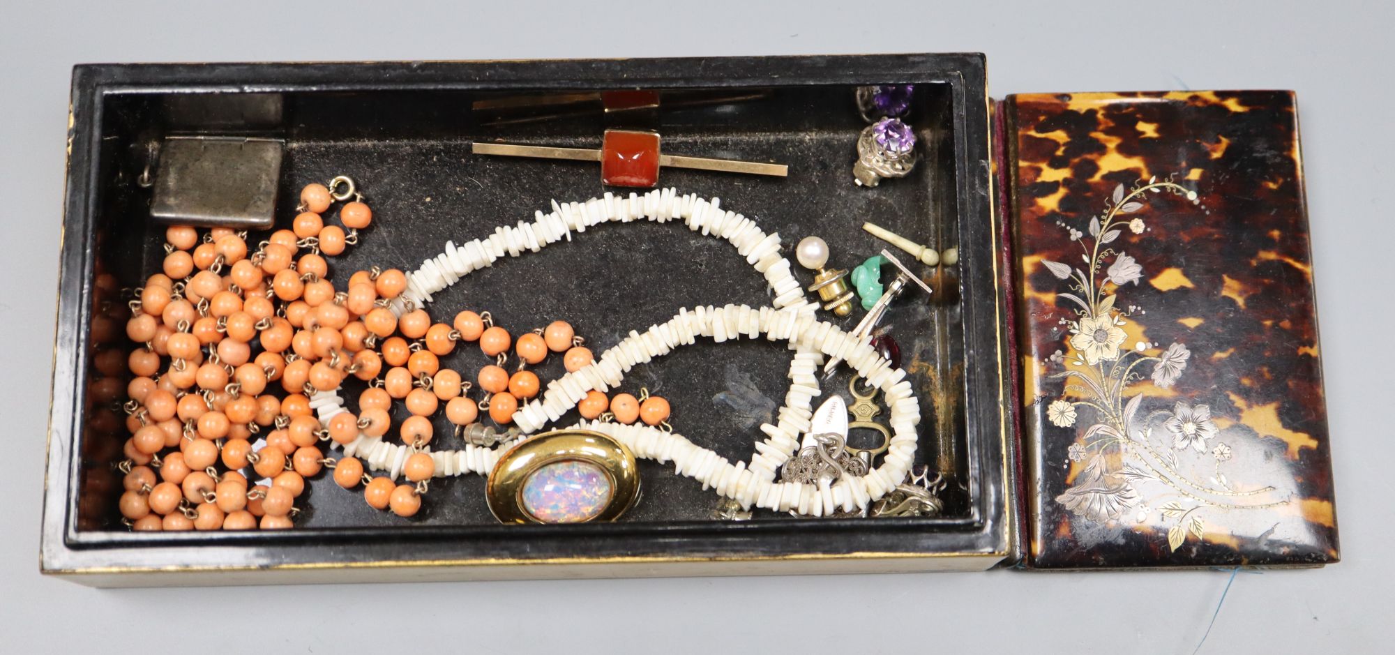 A 9ct and carnelian set tie pin, an Edwardian silver stamp envelope, Chester, 1905(splits), a coral bead necklace, etc.